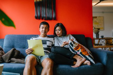 Malay çift kanepede oturup beraber okuduk. Genç, çekici ve rahat onlar onların oturma odasında onların kanepede birlikte hafta sonu zevk gibi olduklarından.