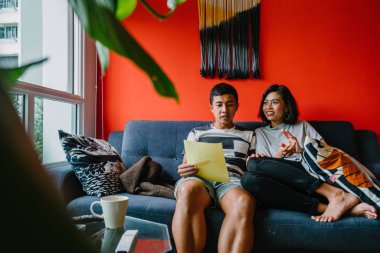 Malay çift kanepede oturup beraber okuduk. Genç, çekici ve rahat onlar onların oturma odasında onların kanepede birlikte hafta sonu zevk gibi olduklarından.