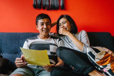 Malay çift kanepede oturup beraber okuduk. Genç, çekici ve rahat onlar onların oturma odasında onların kanepede birlikte hafta sonu zevk gibi olduklarından.