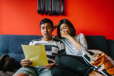 Malay çift kanepede oturup beraber okuduk. Genç, çekici ve rahat onlar onların oturma odasında onların kanepede birlikte hafta sonu zevk gibi olduklarından.