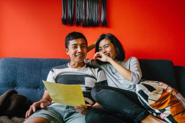 Malay çift kanepede oturup beraber okuduk. Genç, çekici ve rahat onlar onların oturma odasında onların kanepede birlikte hafta sonu zevk gibi olduklarından.