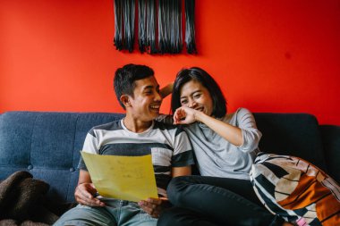 Malay çift kanepede oturup beraber okuduk. Genç, çekici ve rahat onlar onların oturma odasında onların kanepede birlikte hafta sonu zevk gibi olduklarından.