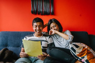 Malay çift kanepede oturup beraber okuduk. Genç, çekici ve rahat onlar onların oturma odasında onların kanepede birlikte hafta sonu zevk gibi olduklarından.