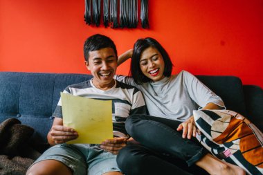 Malay çift kanepede oturup beraber okuduk. Genç, çekici ve rahat onlar onların oturma odasında onların kanepede birlikte hafta sonu zevk gibi olduklarından.