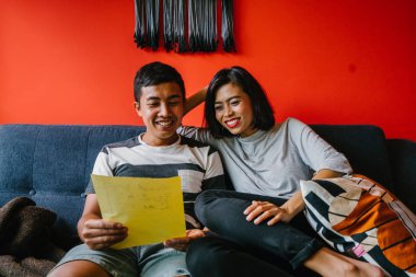 Malay çift kanepede oturup beraber okuduk. Genç, çekici ve rahat onlar onların oturma odasında onların kanepede birlikte hafta sonu zevk gibi olduklarından.