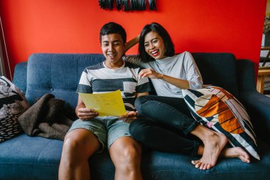 Malay çift kanepede oturup beraber okuduk. Genç, çekici ve rahat onlar onların oturma odasında onların kanepede birlikte hafta sonu zevk gibi olduklarından.