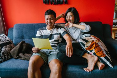 Malay çift kanepede oturup beraber okuduk. Genç, çekici ve rahat onlar onların oturma odasında onların kanepede birlikte hafta sonu zevk gibi olduklarından.