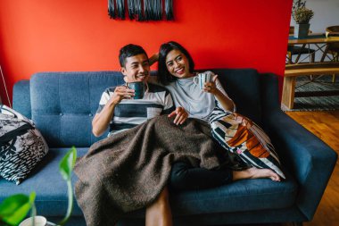 evli Malay çift birlikte modaya uygun ve modern oturma odasında onların kanepede oturup