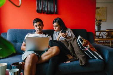 Genç Malay evli çift hafta sonları evde otur. Adam kendi dizüstü bilgisayarında çalışıyor ve onun karısı onun smartphone denetliyor