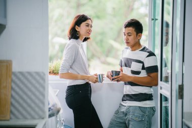 Sıcak bir içecek zevk ve bir başkasına severek konuşurken genç Malay Asya çift. Onlar pencere balkon tarafından gün boyunca birlikte ihale bir an paylaşıyorsunuz.