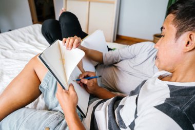 Tembel hafta sonu yatakta oturup bir genç ve çekici Malay Asya çift portresi. 