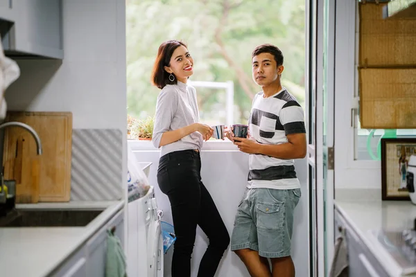 Sıcak bir içecek zevk ve bir başkasına severek konuşurken genç Malay Asya çift. Onlar pencere balkon tarafından gün boyunca birlikte ihale bir an paylaşıyorsunuz.