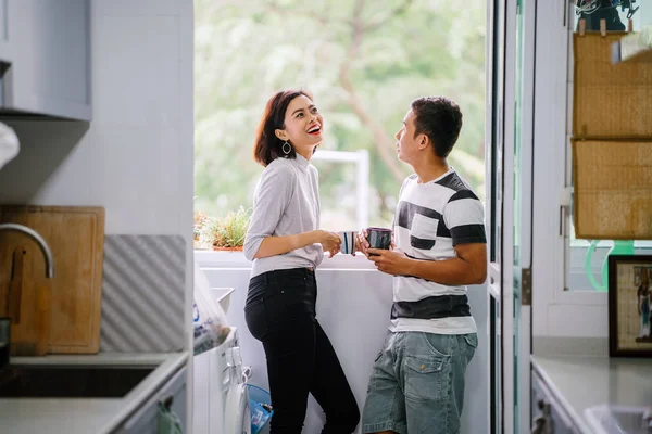 Sıcak bir içecek zevk ve bir başkasına severek konuşurken genç Malay Asya çift. Onlar pencere balkon tarafından gün boyunca birlikte ihale bir an paylaşıyorsunuz.