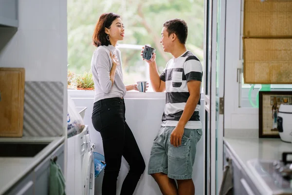 Sıcak bir içecek zevk ve bir başkasına severek konuşurken genç Malay Asya çift. Onlar pencere balkon tarafından gün boyunca birlikte ihale bir an paylaşıyorsunuz.