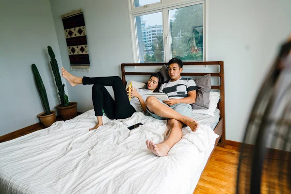 Tembel hafta sonu yatakta oturup bir genç ve çekici Malay Asya çift portresi. 