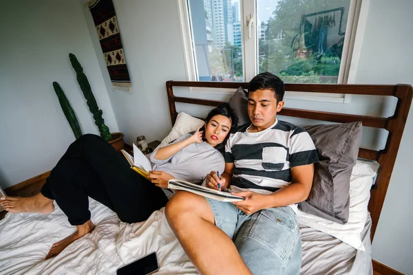 Tembel hafta sonu yatakta oturup bir genç ve çekici Malay Asya çift portresi. 