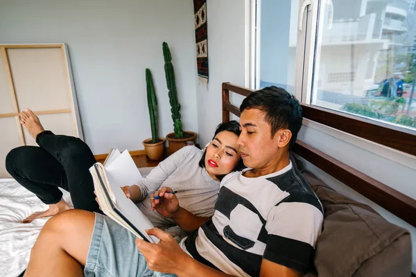 Tembel hafta sonu yatakta oturup bir genç ve çekici Malay Asya çift portresi. 