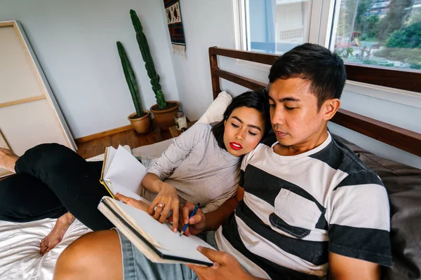 Tembel hafta sonu yatakta oturup bir genç ve çekici Malay Asya çift portresi. 