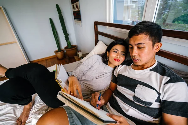 Tembel hafta sonu yatakta oturup bir genç ve çekici Malay Asya çift portresi. 