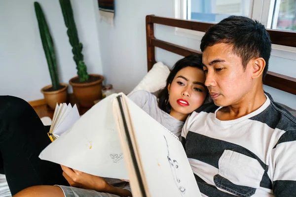 Tembel hafta sonu yatakta oturup bir genç ve çekici Malay Asya çift portresi. 