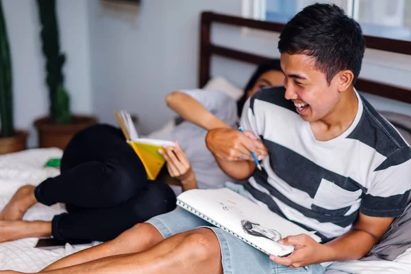 Tembel hafta sonu yatakta oturup bir genç ve çekici Malay Asya çift portresi. 