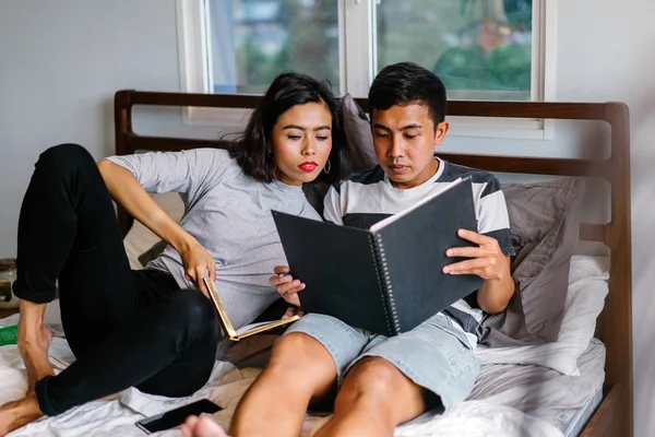 Tembel hafta sonu yatakta oturup bir genç ve çekici Malay Asya çift portresi. 