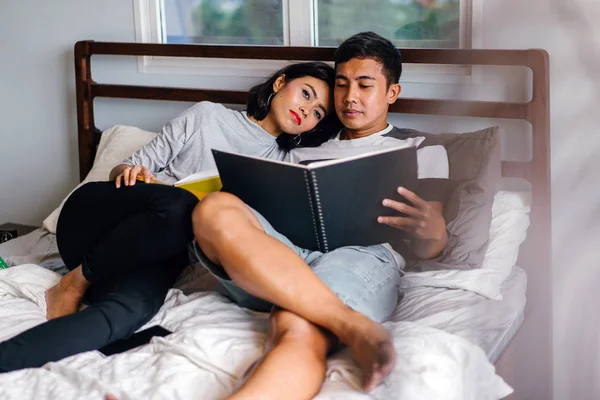 Tembel hafta sonu yatakta oturup bir genç ve çekici Malay Asya çift portresi. 