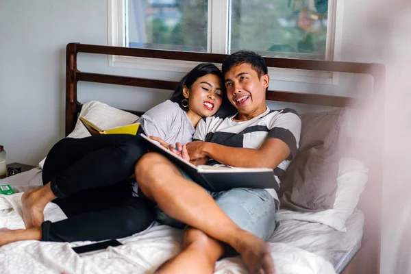 Tembel hafta sonu yatakta oturup bir genç ve çekici Malay Asya çift portresi. 