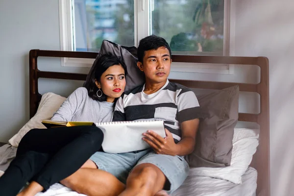 Tembel hafta sonu yatakta oturup bir genç ve çekici Malay Asya çift portresi. 