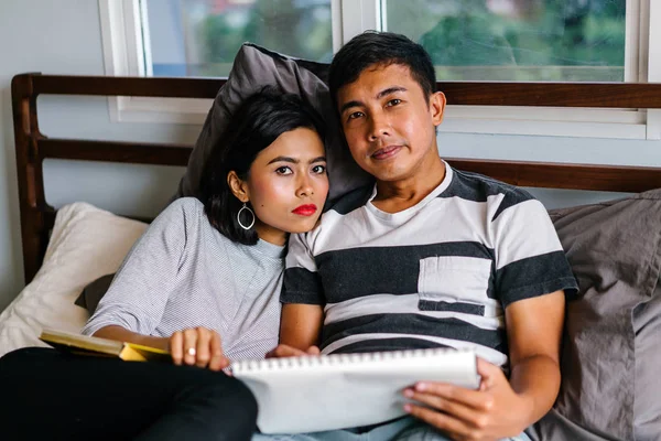 Tembel hafta sonu yatakta oturup bir genç ve çekici Malay Asya çift portresi. 