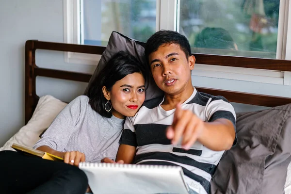 Tembel hafta sonu yatakta oturup bir genç ve çekici Malay Asya çift portresi. 