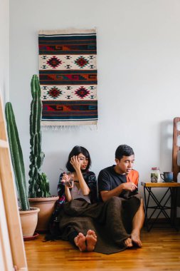 Genç bir Malay çift yatmak ve evlerinde sıcak bir içecek paylaşın. Onlar sarılır up ve birbirleriyle konuşmak gibi zemin ve rahat oturan.