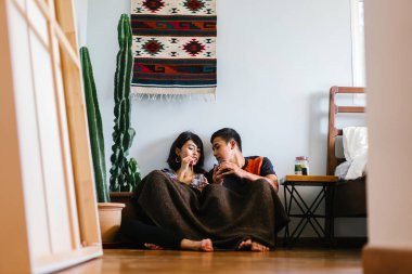 Genç bir Malay çift yatmak ve evlerinde sıcak bir içecek paylaşın. Onlar sarılır up ve birbirleriyle konuşmak gibi zemin ve rahat oturan.