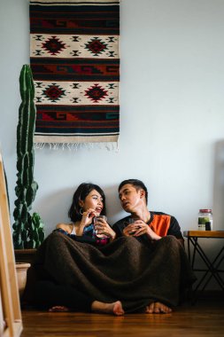 Genç bir Malay çift yatmak ve evlerinde sıcak bir içecek paylaşın. Onlar sarılır up ve birbirleriyle konuşmak gibi zemin ve rahat oturan.