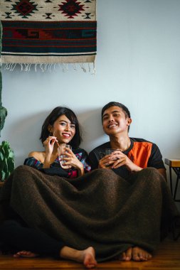 Genç bir Malay çift yatmak ve evlerinde sıcak bir içecek paylaşın. Onlar sarılır up ve birbirleriyle konuşmak gibi zemin ve rahat oturan.