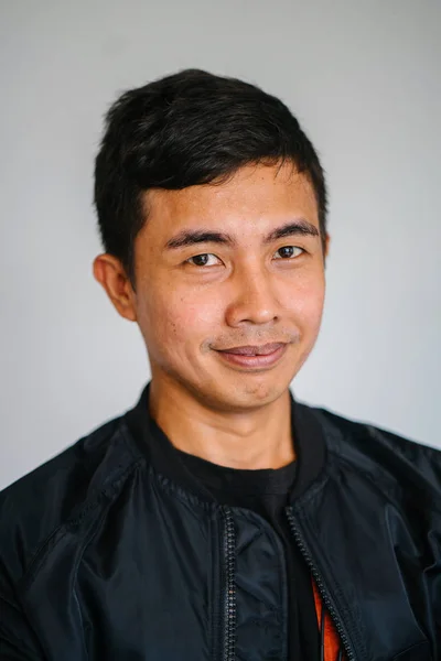 Portrait of a handsome middle-aged Malay Singaporean man in a studio. He is taking his head shot against a white backdrop in a studio.