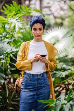 Genç ve çekici Malay Müslüman kadın smartphone elinde tutan 