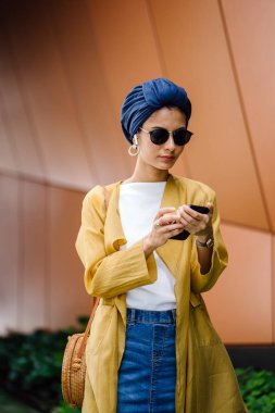 Genç ve çekici Malay Müslüman kadın gündüz elele smartphone