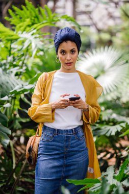 Genç ve çekici Malay Müslüman kadın smartphone elinde tutan 