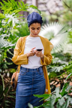 Genç ve çekici Malay Müslüman kadın smartphone elinde tutan 