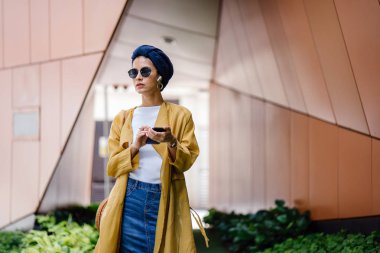 Genç ve çekici Malay Müslüman kadın gündüz elele smartphone