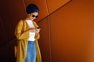 Genç ve çekici Malay Müslüman kadın smartphone elinde tutan 