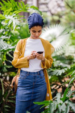 Genç ve çekici Malay Müslüman kadın smartphone elinde tutan 