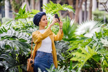 Genç ve çekici Malay Müslüman kadın smartphone elinde tutan 
