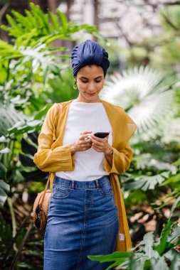 Genç ve çekici Malay Müslüman kadın smartphone elinde tutan 