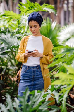 Genç ve çekici Malay Müslüman kadın smartphone elinde tutan 