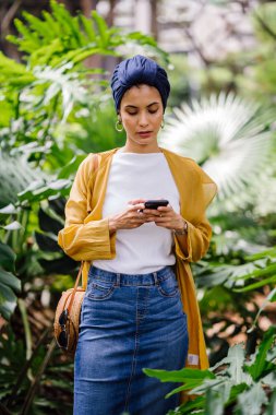 Genç ve çekici Malay Müslüman kadın smartphone elinde tutan 