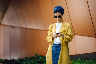 Genç ve çekici Malay Müslüman kadın smartphone elinde tutan 