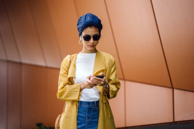 Genç ve çekici Malay Müslüman kadın smartphone elinde tutan 