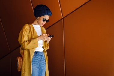 Genç ve çekici Malay Müslüman kadın smartphone elinde tutan 